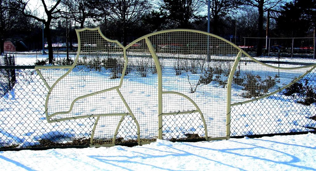 Cream painted dinosaur panel with welded mesh infill above sunlit snow