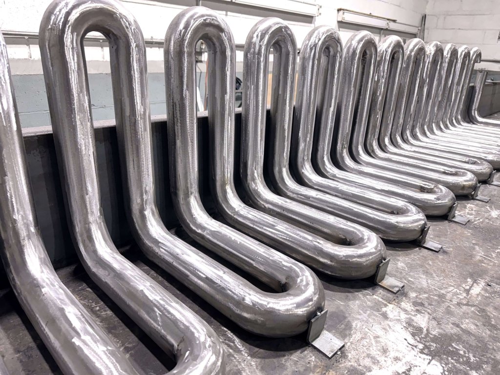 Bare metal hairpin bends welded to base plates on the workshop floor
