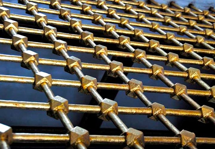 Heavy gold-finished bars crossing in a diamond lattice with faceted collars at each joint